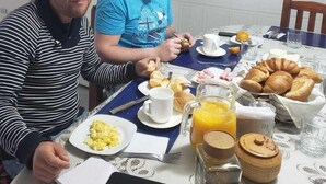 Two people sitting at a table with breakfast items including eggs, croissants, and orange juice. - Hostal Davinci Mitad del Mundo (San Antonio de Pichincha)