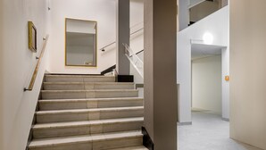 A staircase with a handrail, a wall-mounted mirror, and a light fixture. - Hotel Ruf (Pforzheim)