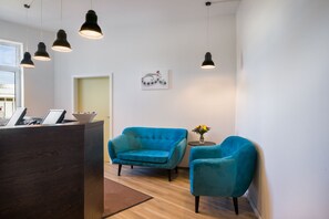 A reception area with a wooden reception desk, two teal armchairs, and pendant lighting.