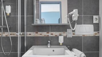 A modern bathroom with a shower, a sink, a mirror, and a hairdryer.