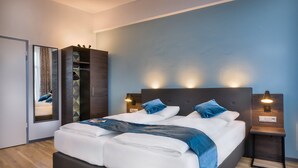 A modern bedroom with a large bed, two bedside tables with lamps, a wardrobe, and a mirror. - Hotel Ruf (Pforzheim)