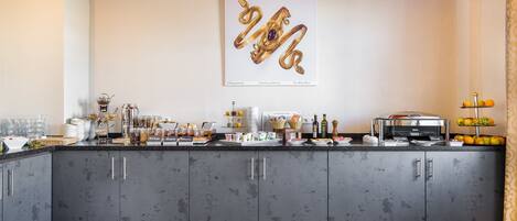 A modern kitchen with grey cabinets, a breakfast bar, and a variety of breakfast items.