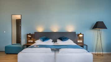 Una habitación de hotel moderna con una cama grande, dos mesitas de noche con lámparas, una lámpara de pie y un espejo grande en la pared.