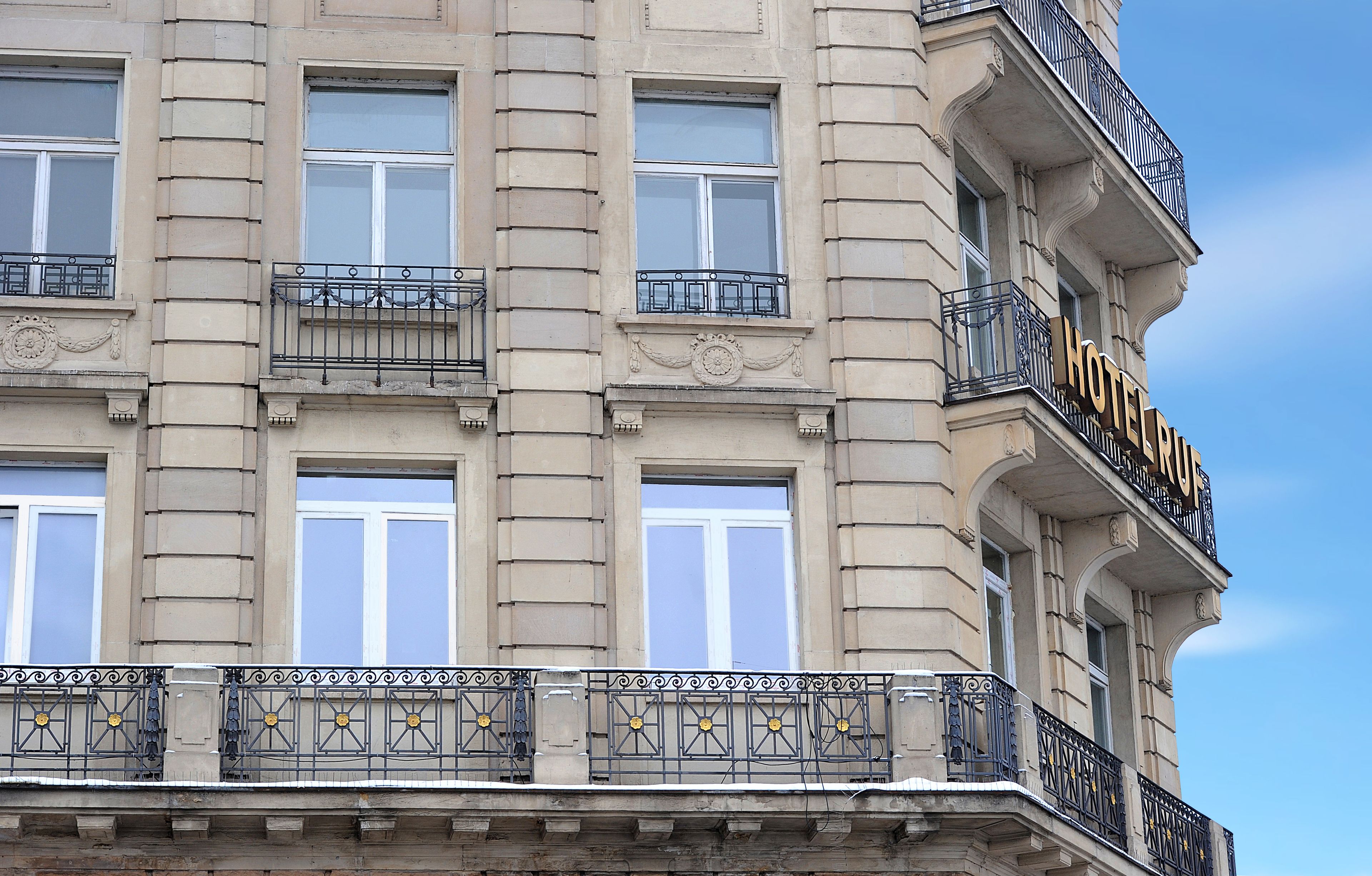 A hotel facade with multiple windows, ornate balconies, and a prominent hotel sign.