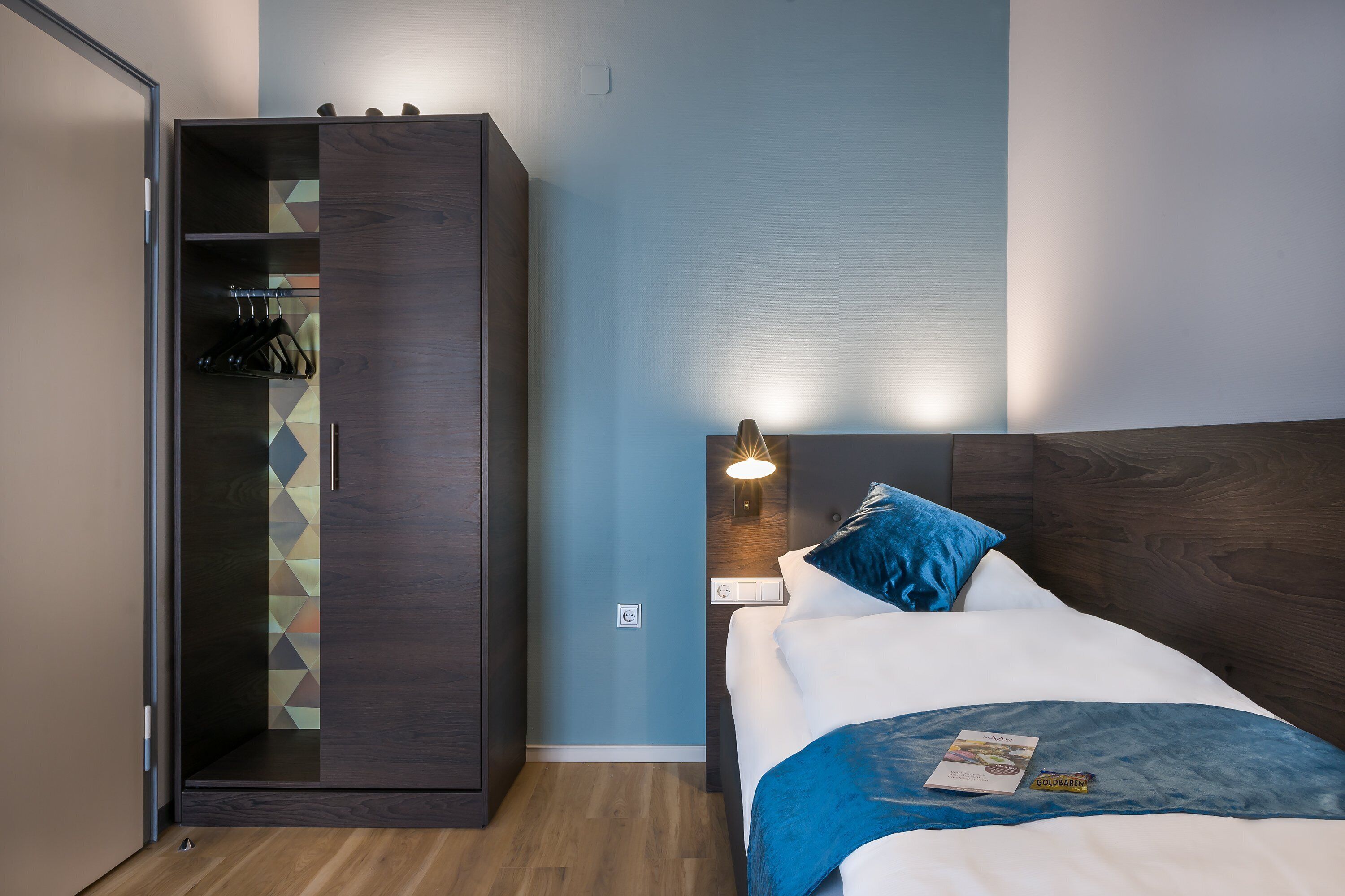 Un dormitorio con cama, armario y mesita de noche con lámpara.
