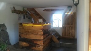 A rustic cabin interior with a wooden staircase leading to a loft area. - Hostel Andino (Villa Pehuenia)