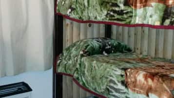 A bunk bed with camouflage bedding in a room with wooden walls and a white cabinet.