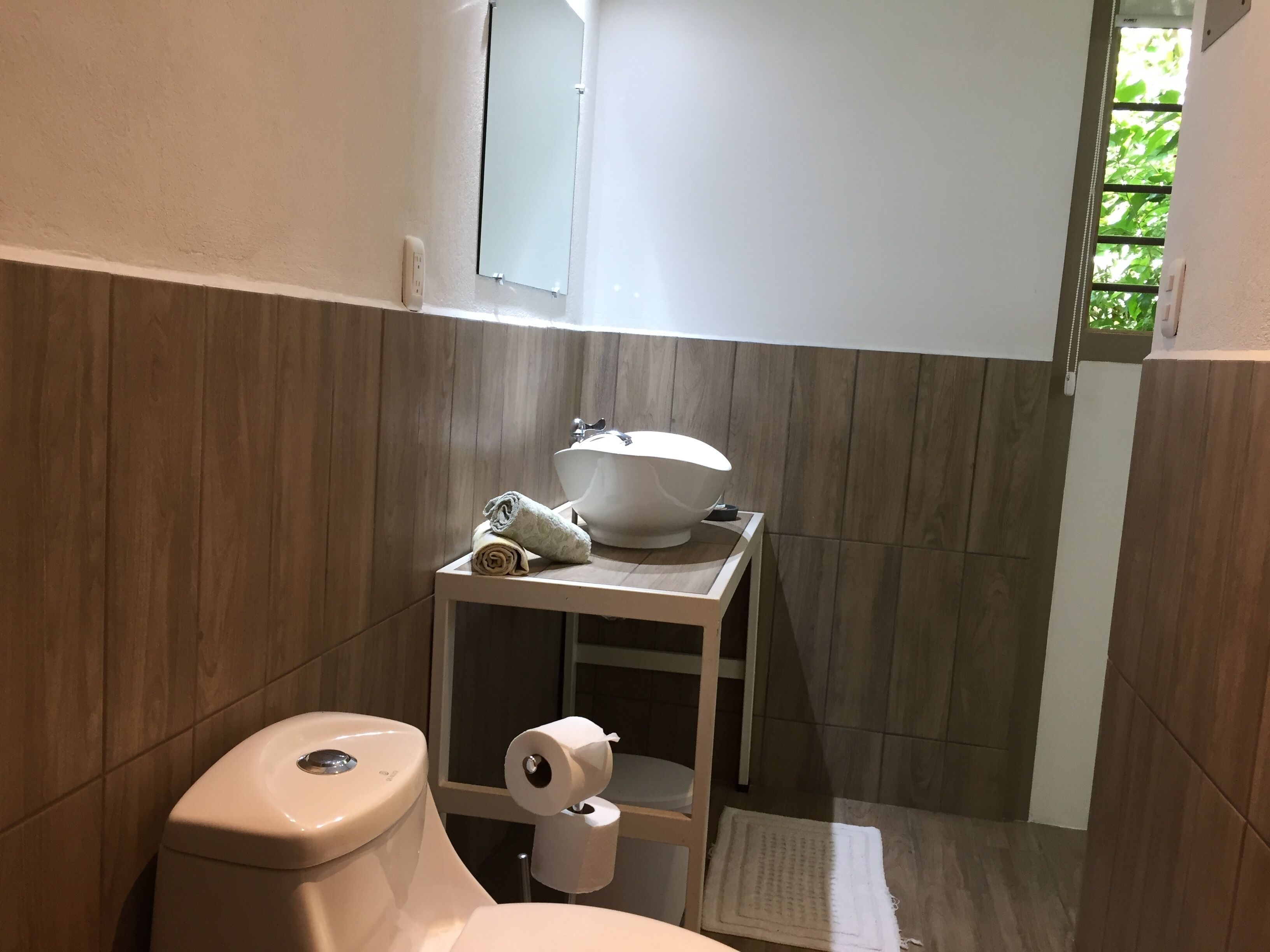 Een kleine badkamer met toilet, wastafel en een klein plankje met handdoeken.