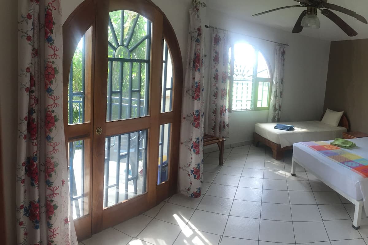 A bedroom with two beds, a ceiling fan, and a window with curtains.