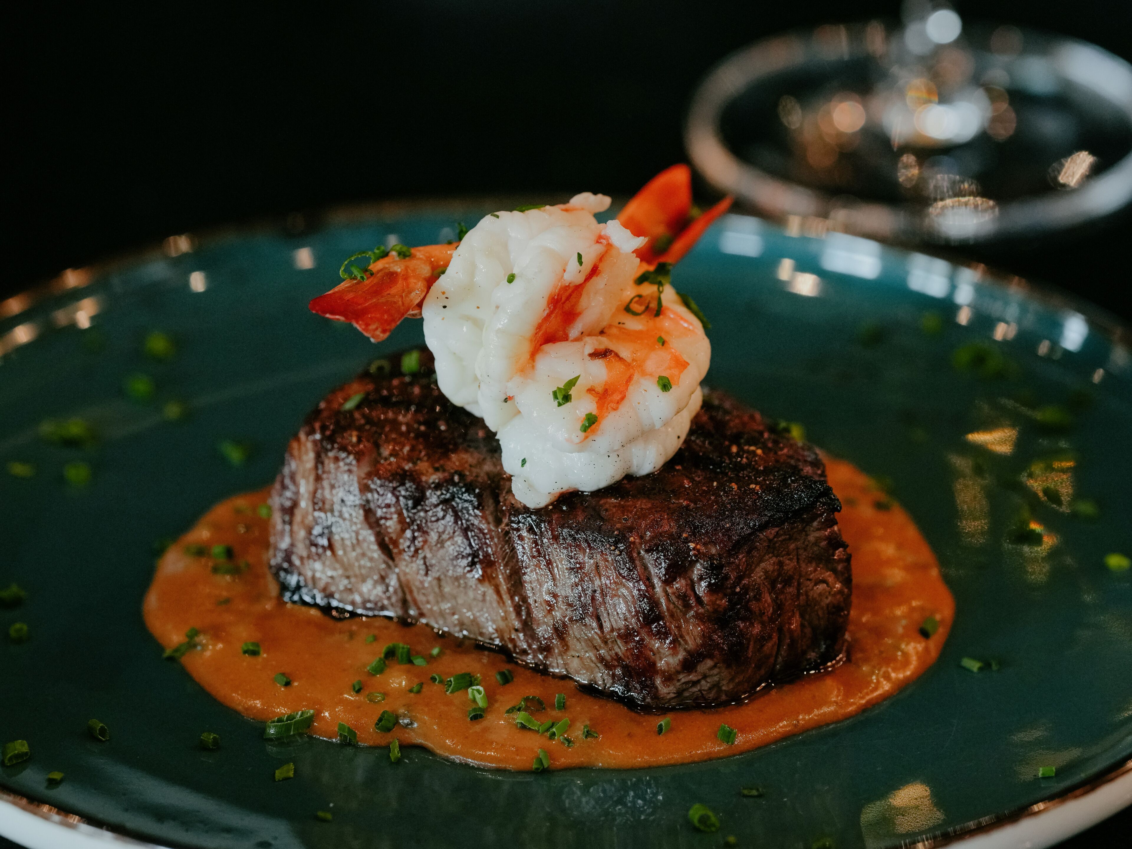 A steak topped with shrimp and sauce on a plate.