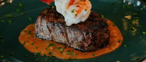 A steak topped with shrimp and sauce on a plate.