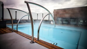 A swimming pool with metal railings, a wooden deck, and a modern building in the background. - OTL Gouverneur Sherbrooke (Sherbrooke)