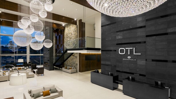 A modern hotel lobby with a large chandelier, a staircase, and a reception desk. - OTL Gouverneur Sherbrooke (Sherbrooke)