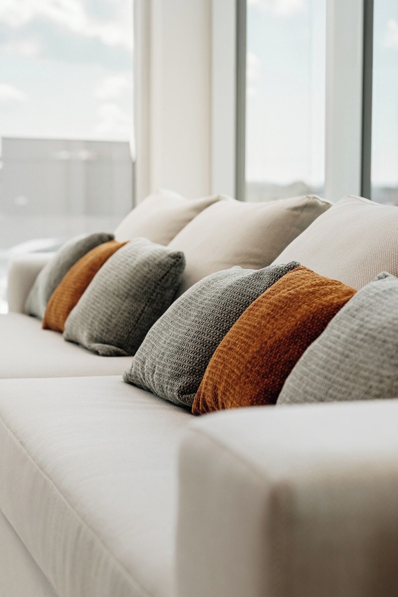 A row of white sofas with grey and brown cushions.