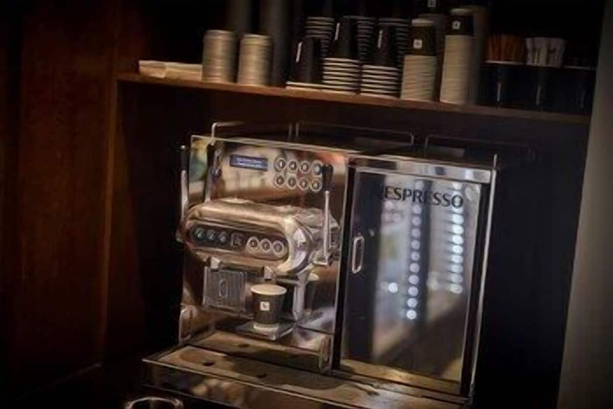Une machine à café dotée d’une enceinte en verre et sur laquelle est inscrit le mot « ESPRESSO ».