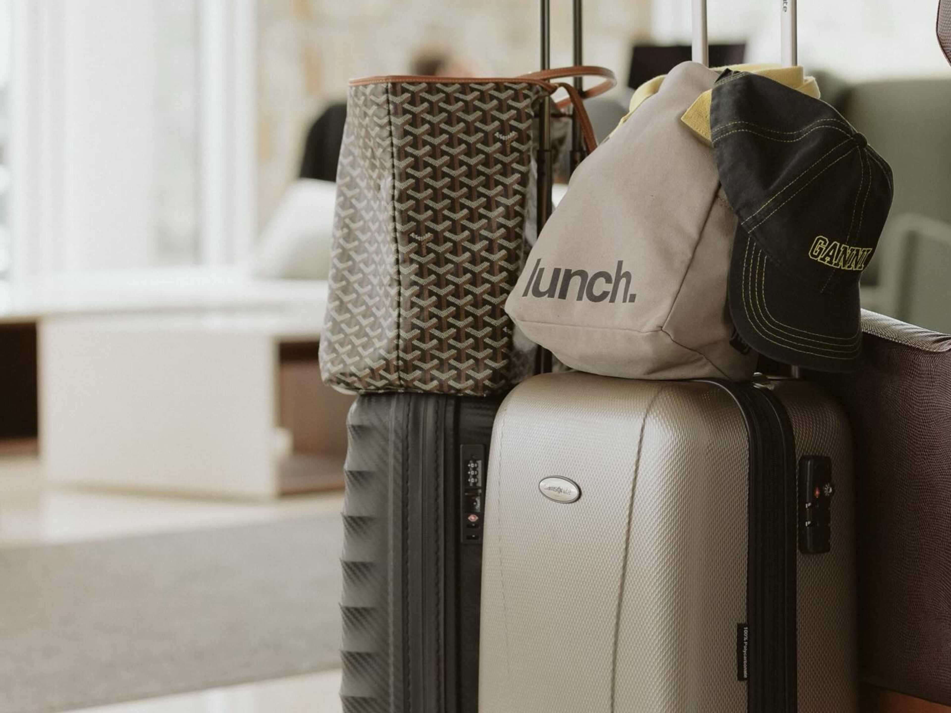 A suitcase with a handle, a patterned bag, and a cap on top.