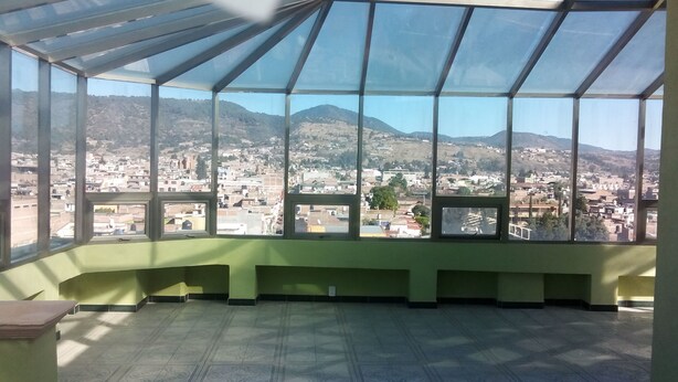 A room with a large window offering a view of a cityscape and mountains. - Hotel Ejecutivo Inn (Ciudad Hidalgo)