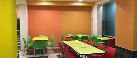 A dining area with tables and chairs, a tiled floor, and a wall with a color gradient.