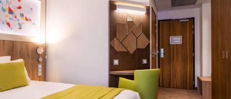 Una habitación de hotel con cama, escritorio, silla y armario.