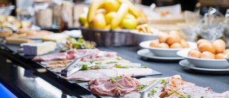 A buffet with various meats, fruits, and eggs.