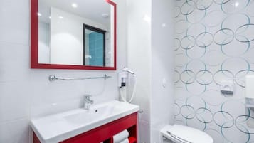 A modern bathroom with a white sink, red vanity, and a toilet.