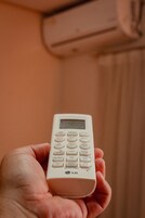 Eine Hand hält eine weiße Fernbedienung mit digitaler Anzeige.