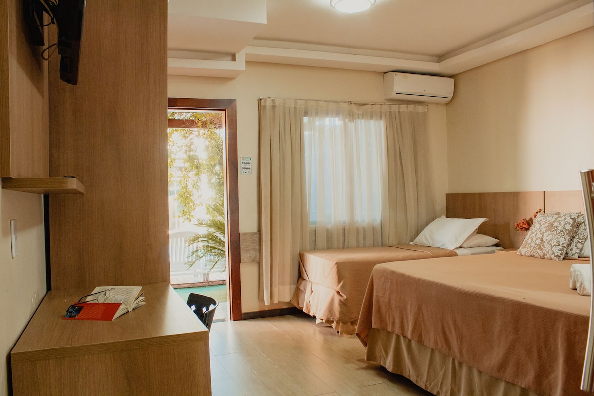 A hotel room with two beds, a desk, and a view of the outdoors.