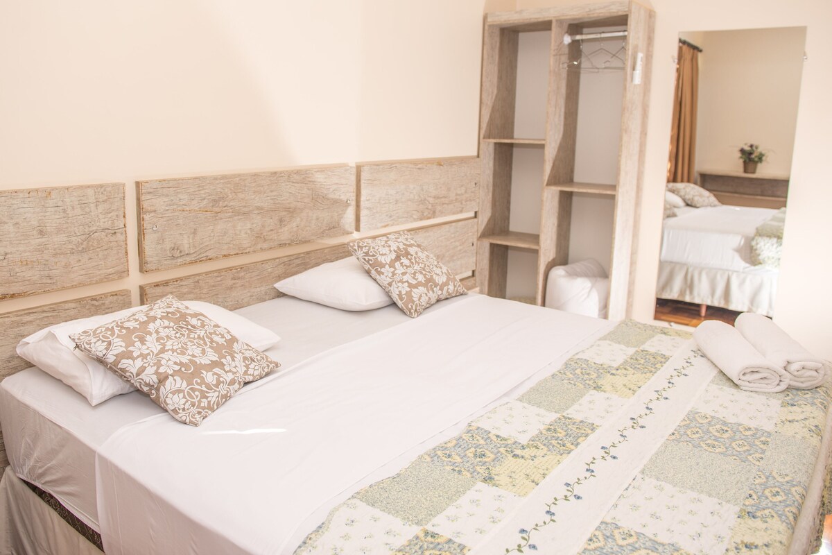 A hotel room with a large bed, a wooden headboard, and a built-in wardrobe.