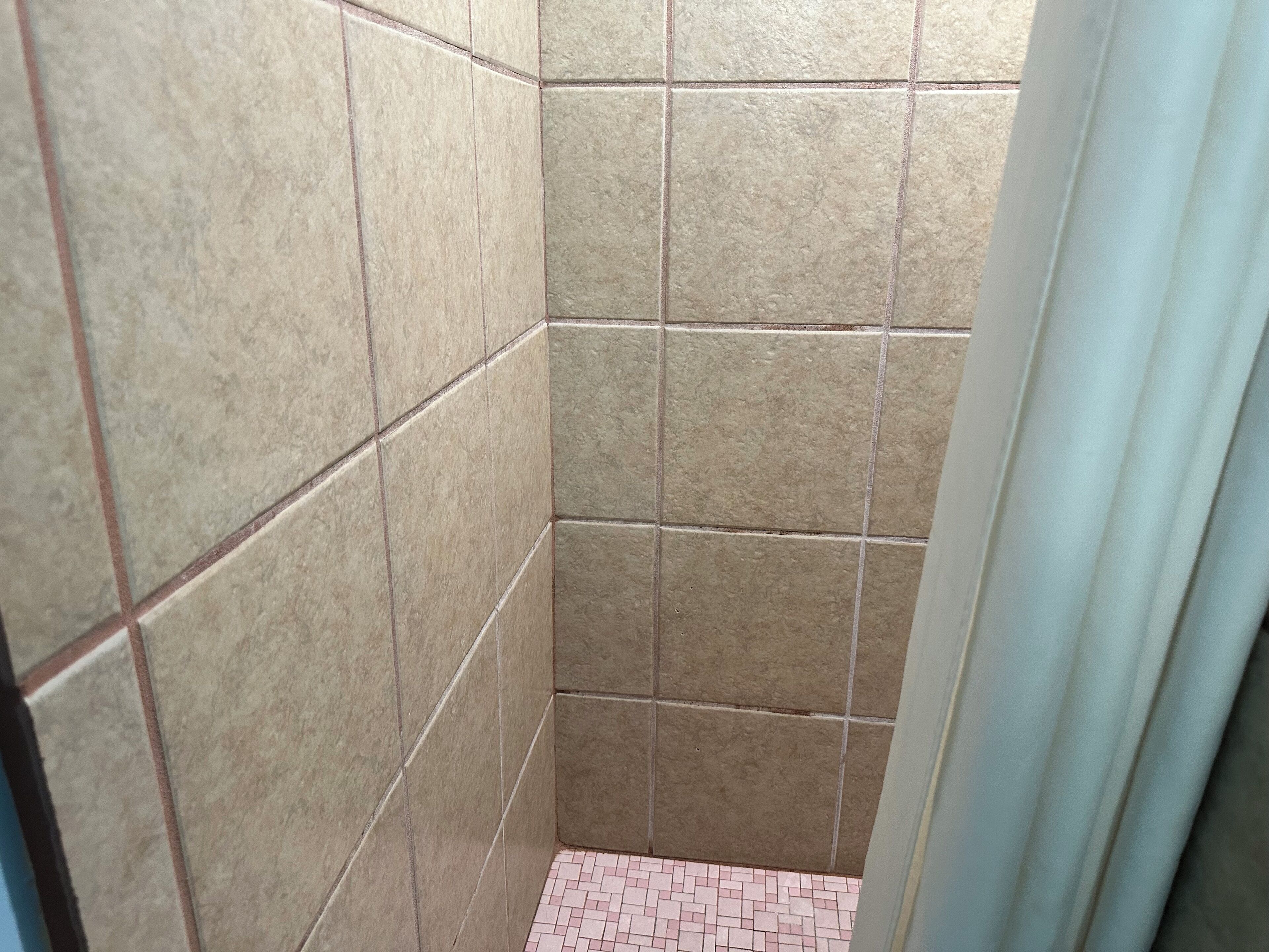 A small, tiled shower area with a pink-tiled floor.