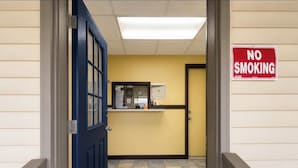 A reception area with a 'NO SMOKING' sign, a reception desk, and a door leading to another room. - Westgate Manor Motel Austintown-Younstown, Ohio (Austintown)