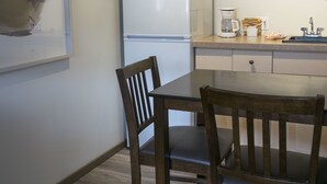 A compact kitchen with a refrigerator, microwave, and coffee maker. There is a wooden dining table with chairs. - Yamnuska Suites (Dead Man's Flats)
