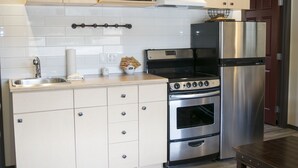 A modern kitchen with white cabinets, a stainless steel refrigerator, a microwave, and a stove. - Yamnuska Suites (Dead Man's Flats)