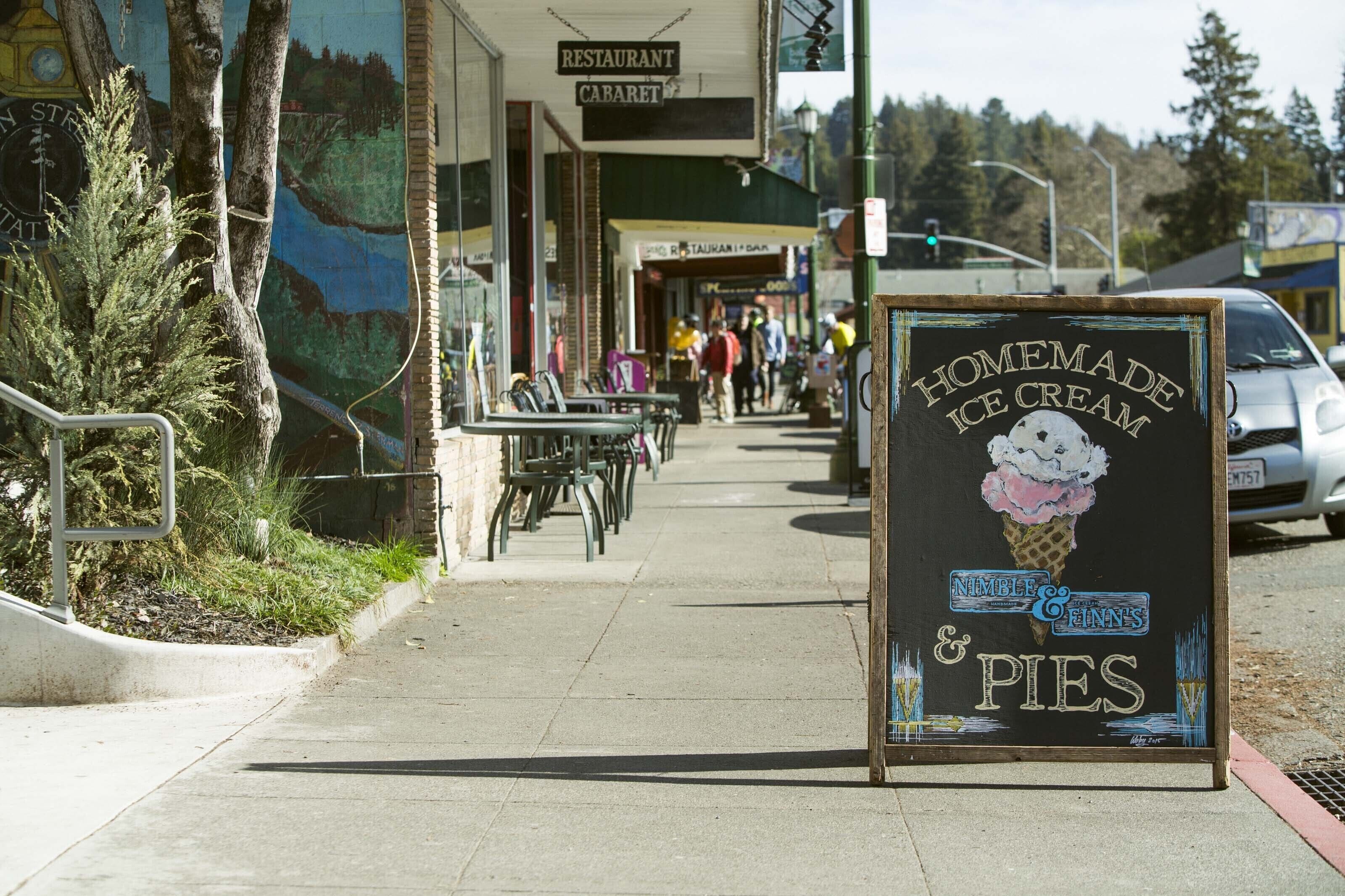 A sidewalk with outdoor seating, a sign for a restaurant, and a sign for homemade ice cream and pies.