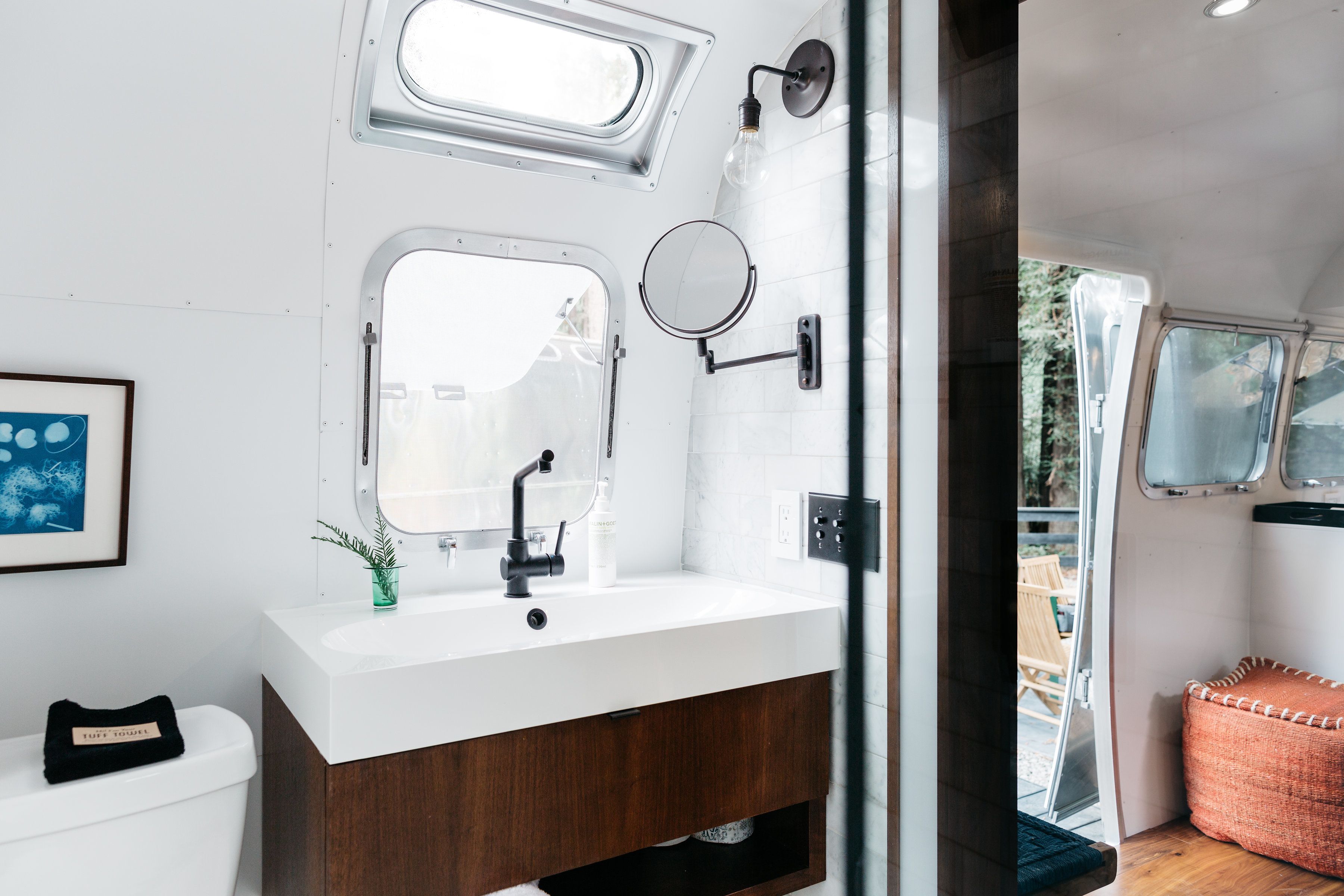 Une salle de bain moderne avec un lavabo blanc, un miroir et une fenêtre.
