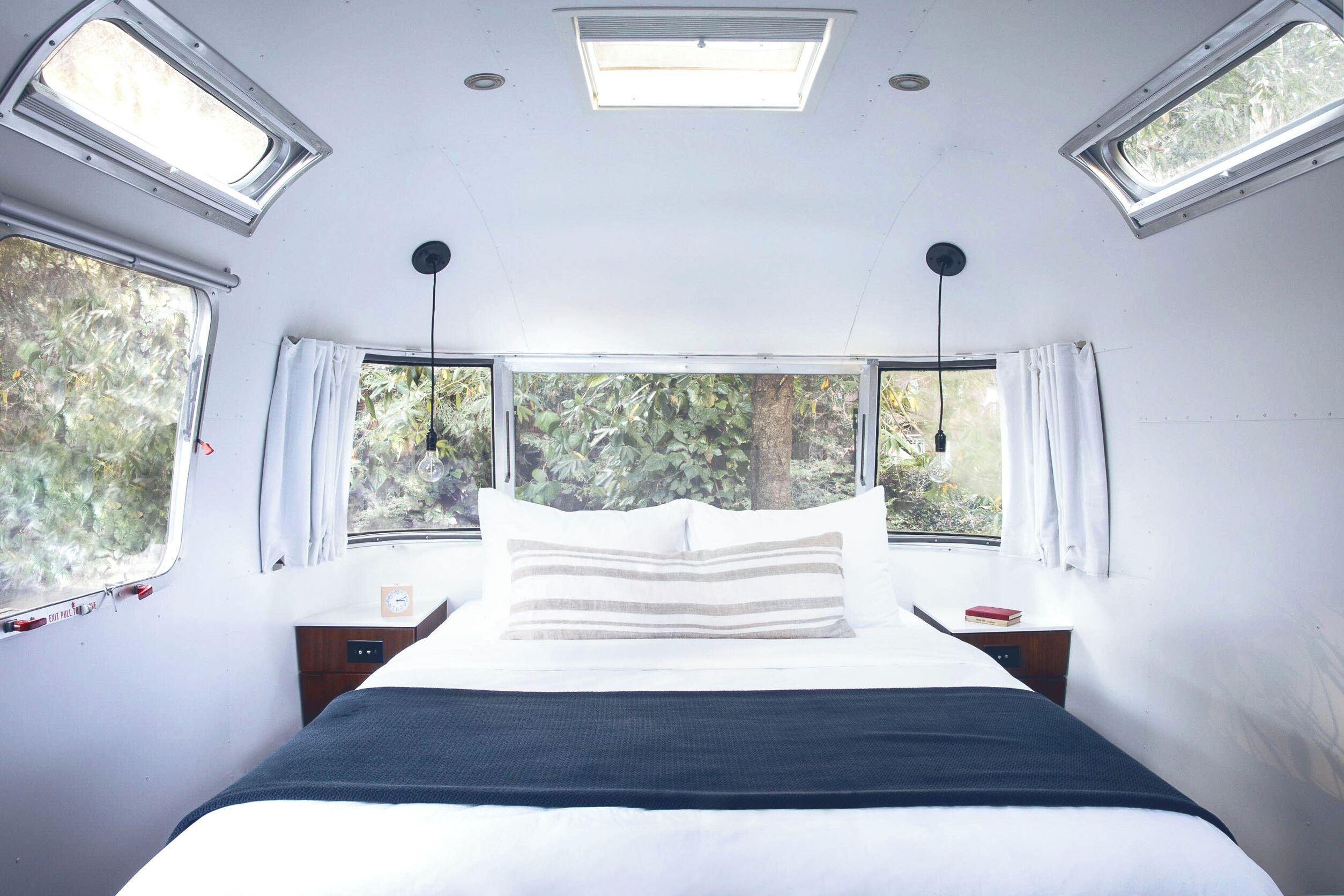 A bedroom with a bed, two bedside tables, a window, and a skylight.