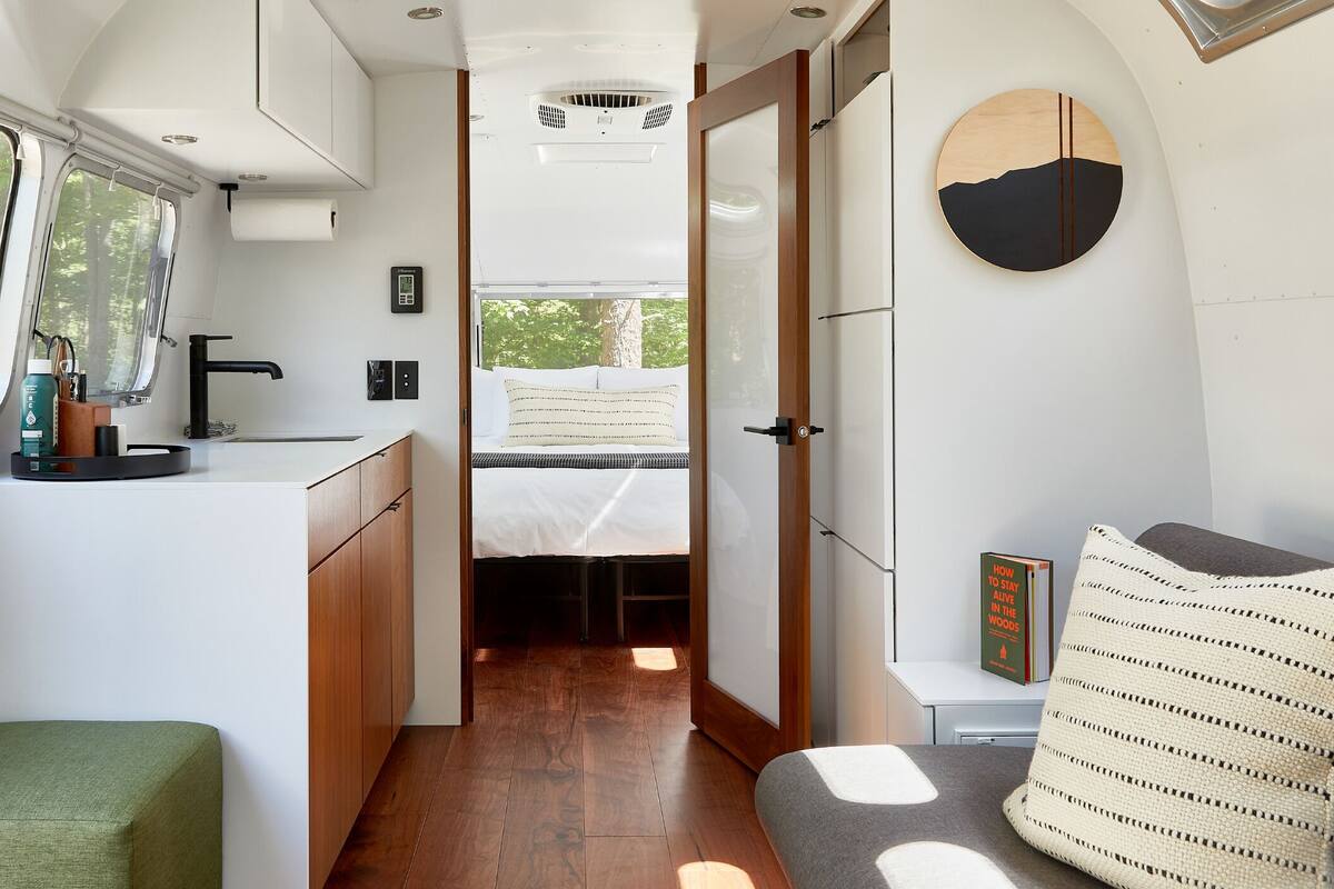 A compact RV interior with a kitchenette, a bed, and a seating area.