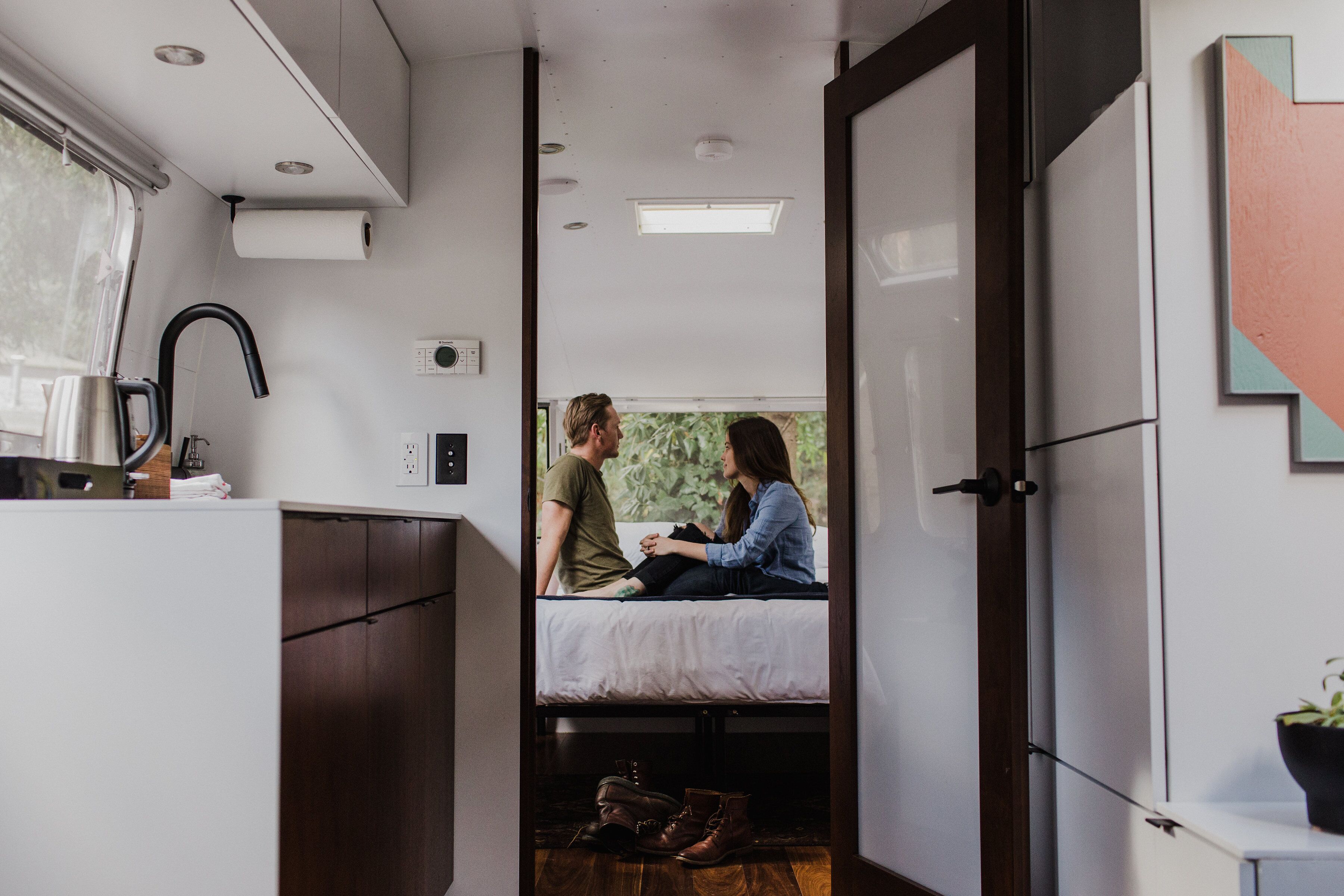 A compact room with a bed, a small kitchenette, and a window providing natural light.