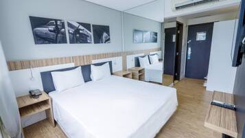 Quarto de hotel com uma cama grande, mesas de cabeceira, escrivaninha e televisão.