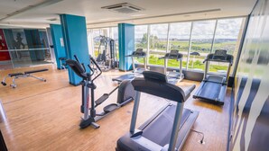 A gym with treadmills, ellipticals, and a view of the countryside through large windows.