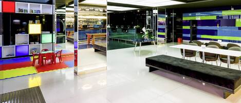 A modern indoor space with a seating area, tables, and a variety of shelves and displays.