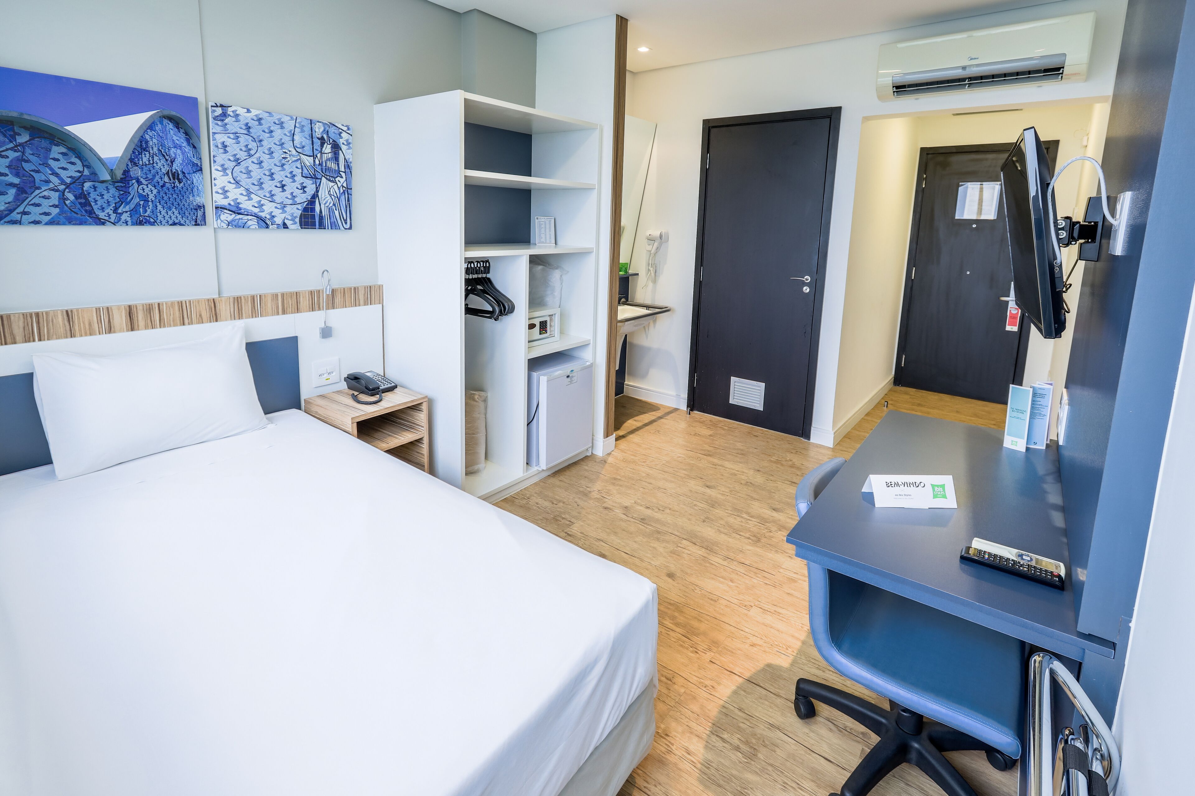 Habitación de hotel con cama, escritorio, silla, armario y baño.
