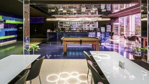 Zona de bar moderna con mesa de billar, asientos y barra provista de distintos artículos.