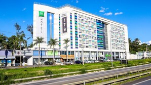 A modern hotel with a prominent "HOTEL" sign, multiple floors, and a parking lot with several cars.