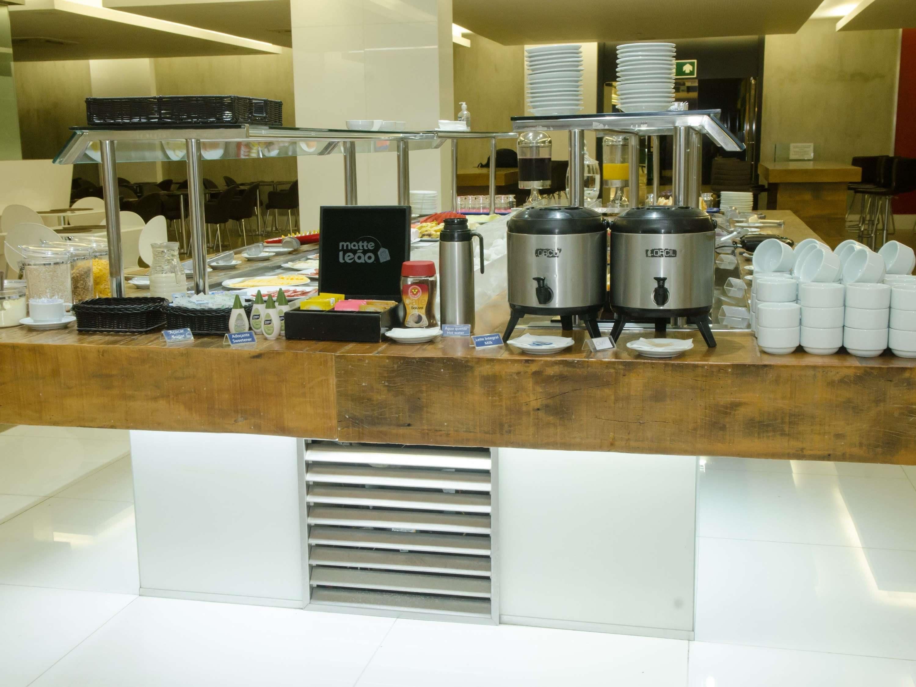 A buffet counter with self-serve stations, including a coffee machine, hot and cold beverage dispensers, and a variety of condiments.