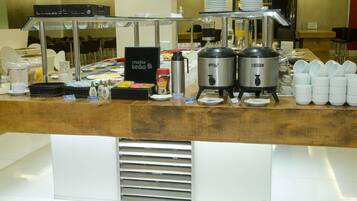 A buffet counter with self-serve stations, including a coffee machine, hot and cold beverage dispensers, and a variety of condiments.