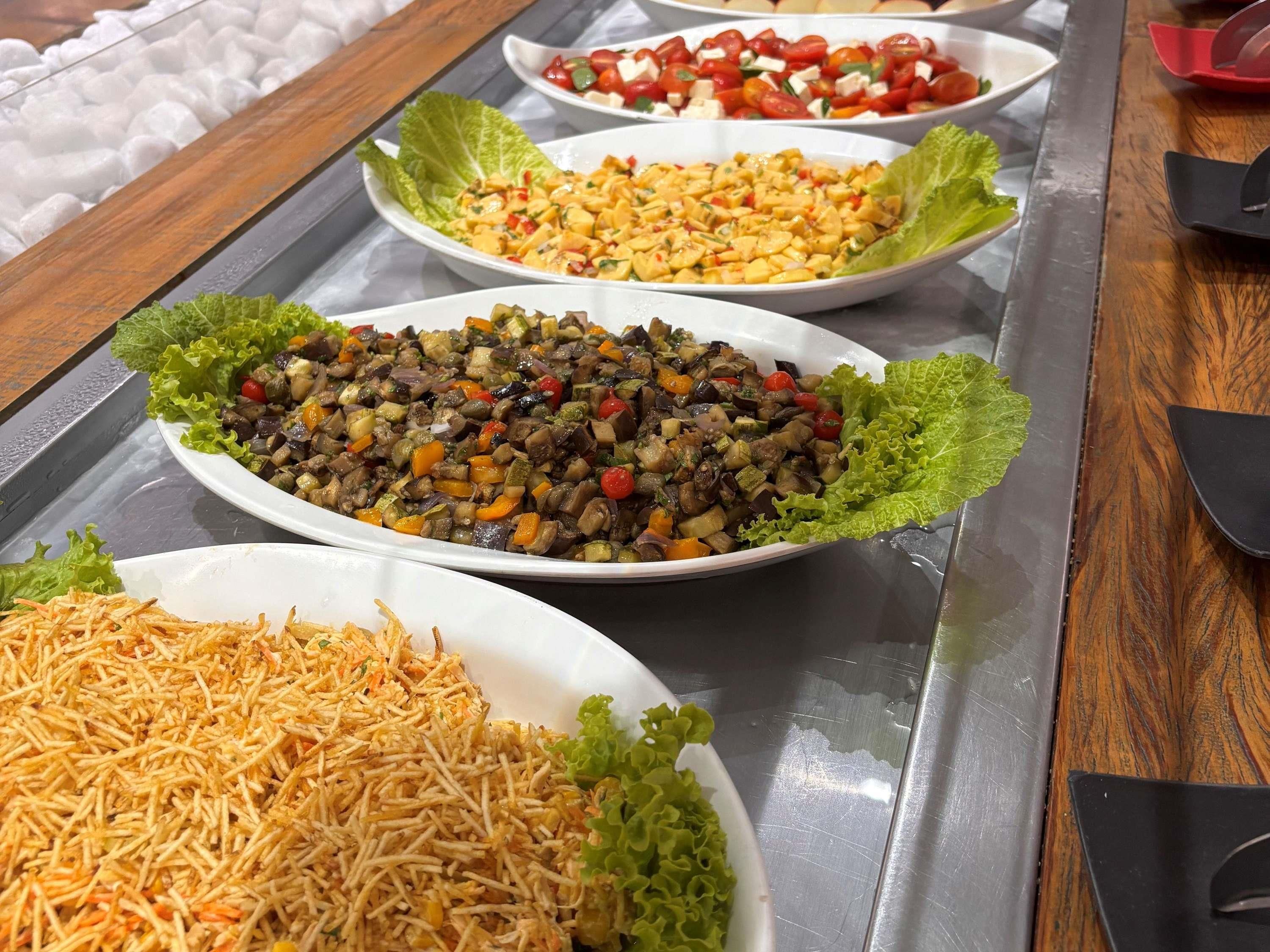 A buffet with various dishes, including a salad, a vegetable mix, and a rice dish.