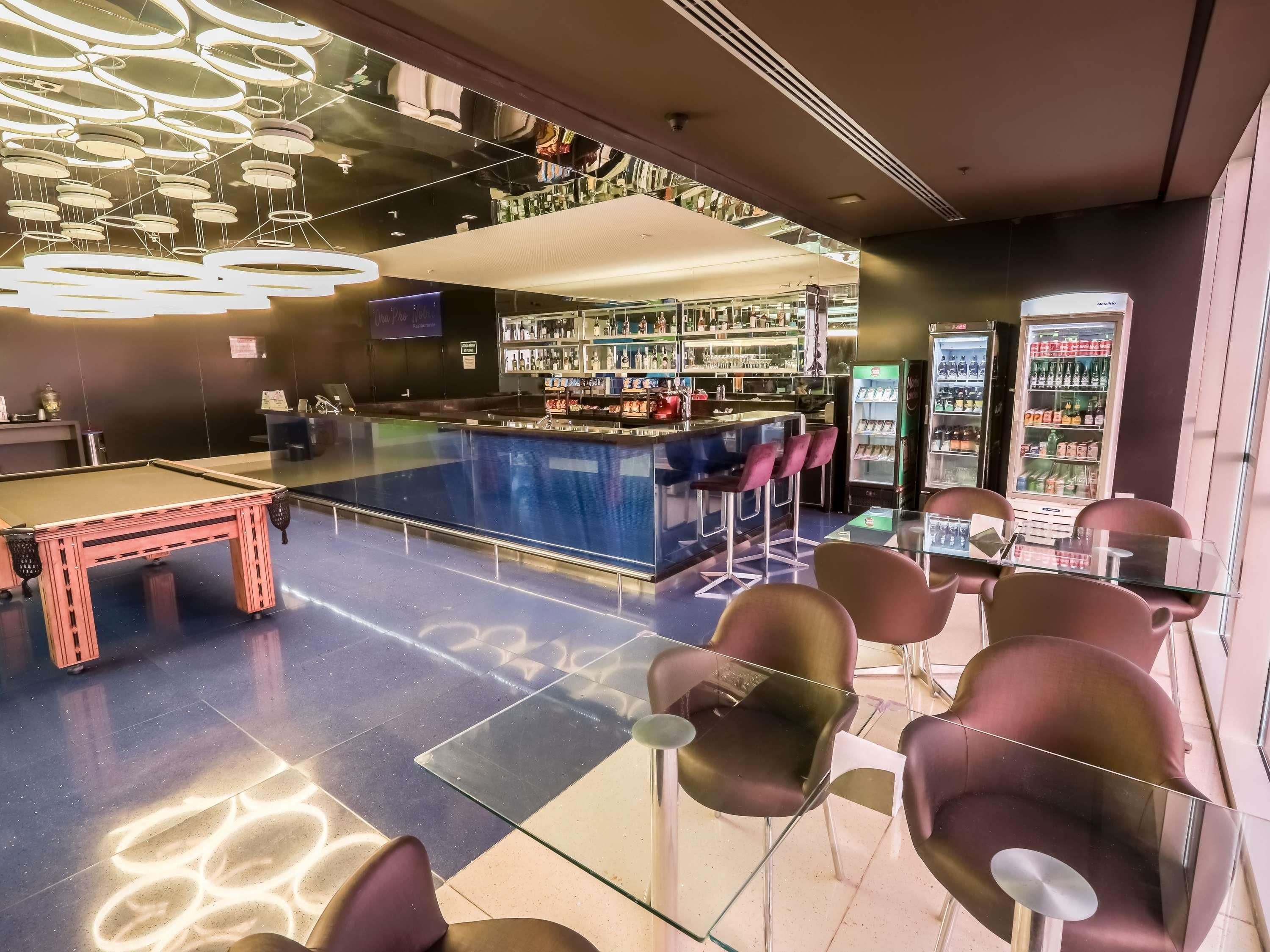 Zona de bar con mesa de billar, taburetes y un área de estar con sillas.