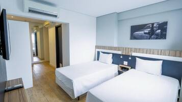 A hotel room with two beds, a TV, and an air conditioning unit.