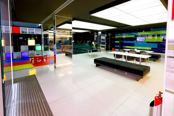 A modern office space with a glass partition, a bar area, and a seating area with tables and chairs. - ibis Styles Confins Aeroporto (Lagoa Santa)