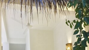 Una sala de estar moderna con un sofá blanco, cojines coloridos, una planta en maceta y un aplique de pared.